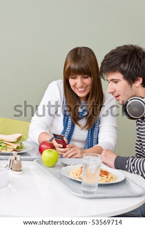 Student cafeteria - teenage couple with mobile phone during lunch break