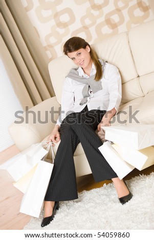 Smiling business woman with shopping bag sitting on sofa in lounge
