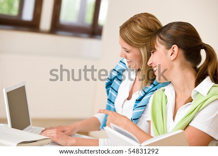 Student at home - two woman with book and laptop study together
