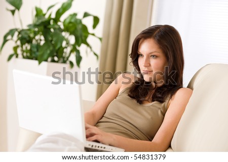 Smiling woman sitting with laptop on sofa in lounge