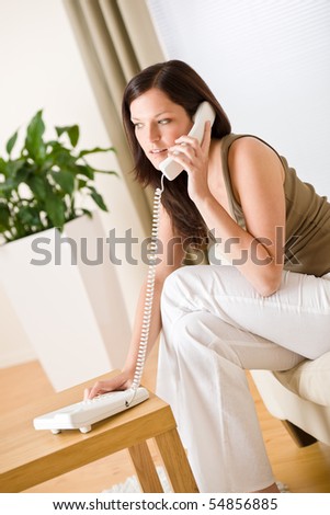 On the phone home - Young woman calling sitting on sofa in lounge