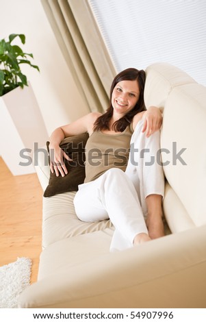 Young happy woman relax lying down on sofa in lounge
