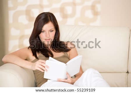 Young woman read book relaxing on sofa in lounge