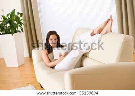 Young woman read book relaxing on sofa in lounge