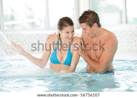 Young sportive couple have fun under water stream in swimming pool