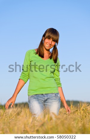 Young woman in sunset corn field with daisy