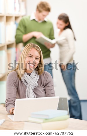 High school library - happy female student with laptop and book