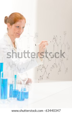 Woman scientist in laboratory write chemical formula with test bue and beaker