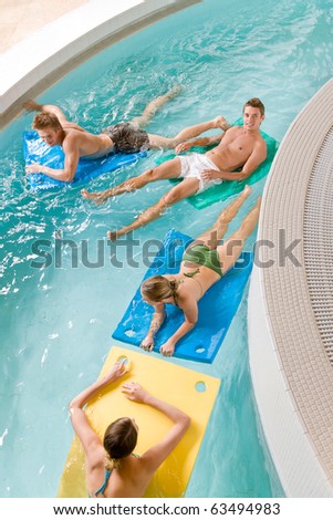 Swimming pool - young people have fun, lying on floating foam matress