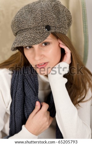 Portrait of Hispanic fashion model wearing cap sitting on antique armchair