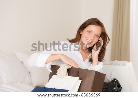 Woman on phone - back home from shopping sitting on bed