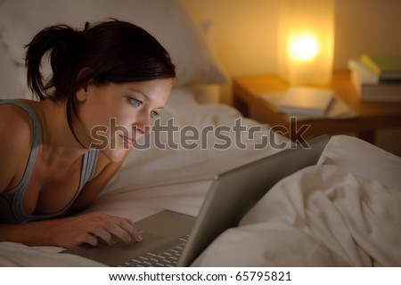 Bedroom evening - woman with laptop lying down in bed