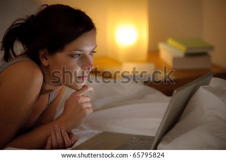 Bedroom evening - woman with laptop lying down in bed