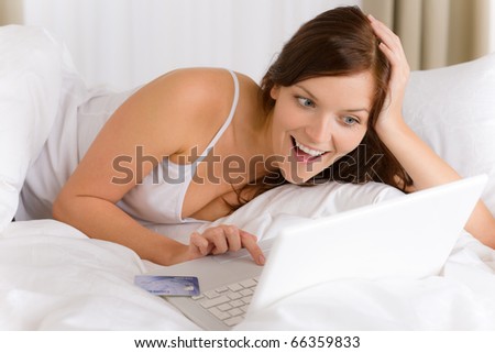 Home online shopping - woman with credit card lying down in white bed