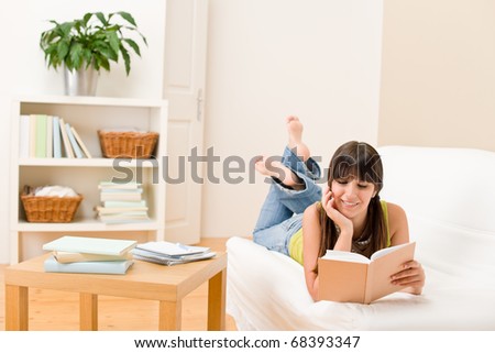 Teenager girl home - student read book laying on sofa