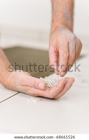 Home improvement, - close-up of handyman placing tile spacer