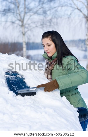 Winter car - woman remove snow from windshield with snow brush