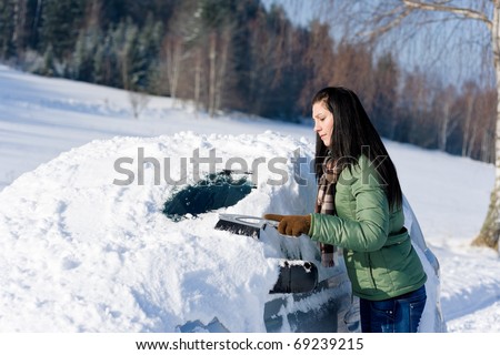 Winter car - woman remove snow from windshield with snow brush