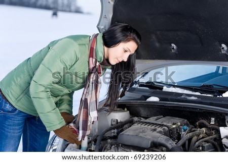 Winter car breakdown - woman try to repair motor