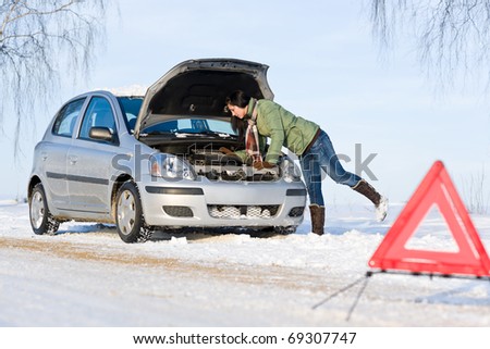 Winter car breakdown - woman try to repair motor