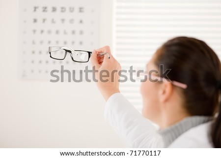 Optician doctor woman with prescription glasses and eye chart
