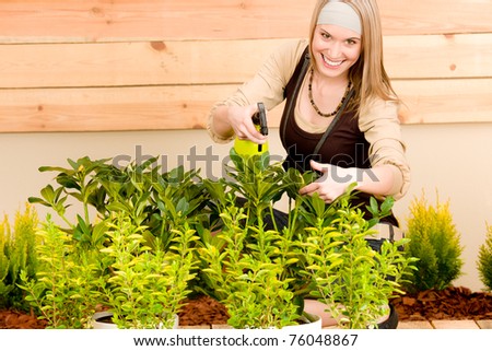 Gardening woman watering plants in spring on terrace