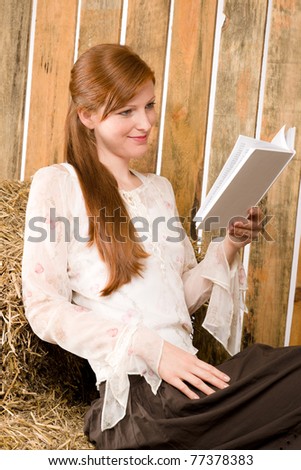 Young romantic red-hair woman reading book sitting in barn country