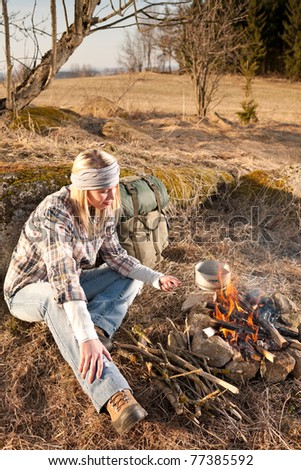 Campfire hiking woman with backpack cook in countryside