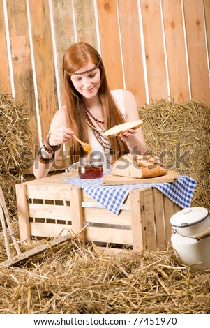 Redhead young hippie woman have breakfast on hay in barn