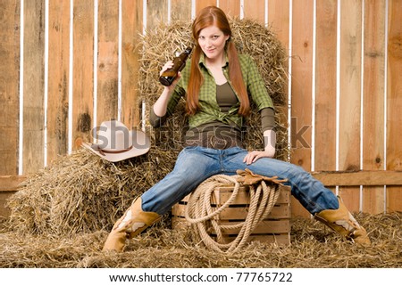 Provocative young cowgirl drink beer in barn country style
