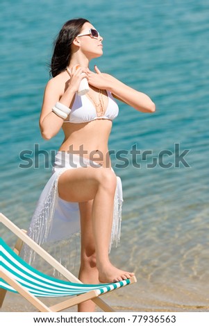Summer young woman apply cream wear bikini on beach