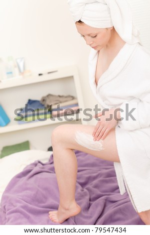 Young student girl apply body cream on her legs