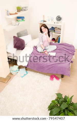Student apartment - young girl speaking on phone sitting on bed