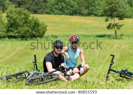 Sport mountain biking couple relax in meadows sitting drink water