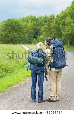 Hiking young couple backpack on asphalt road countryside