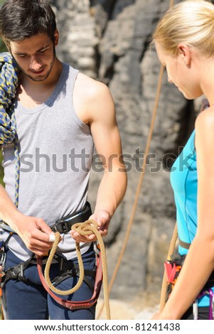 Rock climbing active young man showing mountaineer woman rope knot