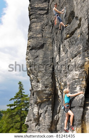 Rock climbing male instructor hold rope blond woman hanging