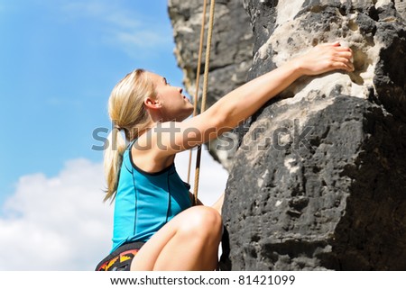 stock photo Rock climbing blond woman on rope sunny day