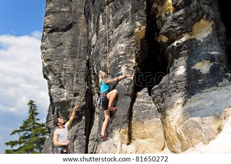 Rock climbing male instructor hold rope blond woman sunny day