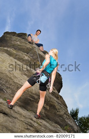 Rock climbing active young woman  man holding rope on top