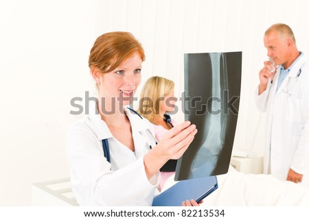 Medical doctors look at x-ray hospital patient in bed broken arm