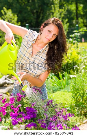 Gardening smiling woman watering violet flowers with can