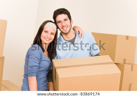Happy young couple moving into new home carrying cardboard boxes