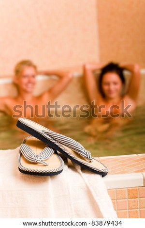 Flip-flops close-up relax spa pool two naked women inside water