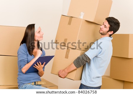 Happy young couple moving into new home carrying cardboard boxes