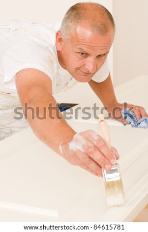 Home decorating mature man painting white door with paint brush