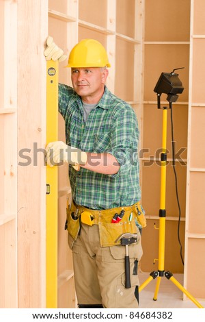 Handyman mature professional with spirit level working on home renovations