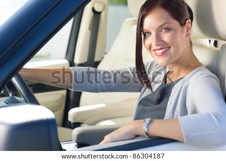 Attractive elegant businesswoman driving luxury car smiling at camera