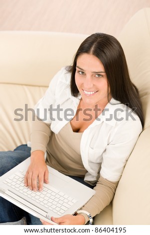 Attractive woman with laptop sitting on couch smiling
