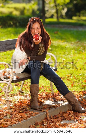 Autumn fashion smiling beautiful woman eat apple sunset nature park